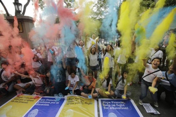 Young Filipinos, led by the Student Christian Movement, throw colored powder in the air as they prepare a joyous welcome for Pope Francis. Photo from Yahoo Philippines.